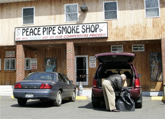 An unidentified man loads cigarettes into a dark plastic bag outside of Rodney Morrison's Peace Pipe Smoke Shop at the Poospatuck Indian reservation near Mastic, N.Y., in this 2008 photo. 